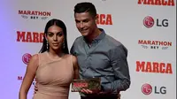 Cristiano Ronaldo bersama kekasihnya Georgina Rodriguez berpose setelah meraih penghargaan MARCA Legend award di Reina Victoria Theater, Madrid (30/7/2019). Di acara tersebut Ronaldo mengaku berharap dapat kembali ke Real Madrid. (AFP Photo/Javier Soriano)