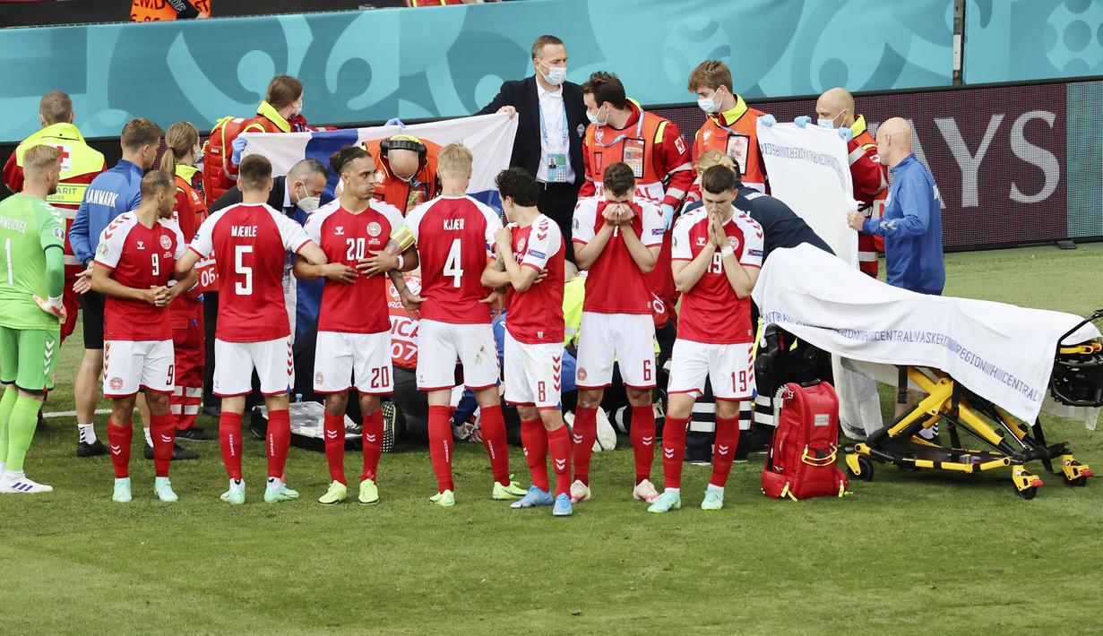 Para pemain Denmark membuat brikade untuk menutupi Christian Eriksen yang jatuh pingsan saat melawan Finlandia pada laga Piala Eropa di Stadion Parken (12/6/2021). (AFP/Wlofgang Ratttay)