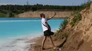 Pengunjung berswafoto dengan latar belakang tempat pembuangan abu dari pabrik batubara lokal di Danau Novosibirsk, Rusia, Kamis (11/7/2019). Dasar danau itu cukup dalam dan berlumpur, sehingga jika sudah tenggelam akan sulit menyelamatkan diri. (Rostislav NETISOV/AFP)