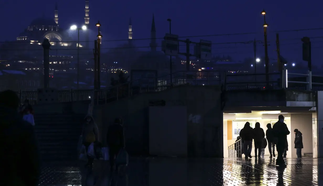 Pejalan kaki melintasi lorong di sebelah masjid Suleymaniye saat hujan salju di Istanbul, Turki, Sabtu (12/3/2022). Salju tebal menutupi Istanbul dan mengganggu lalu lintas udara menyebabkan transportasi laut serta darat terhenti, hingga memaksa penutupan sekolah. (AP Photo/Emrah Gurel)