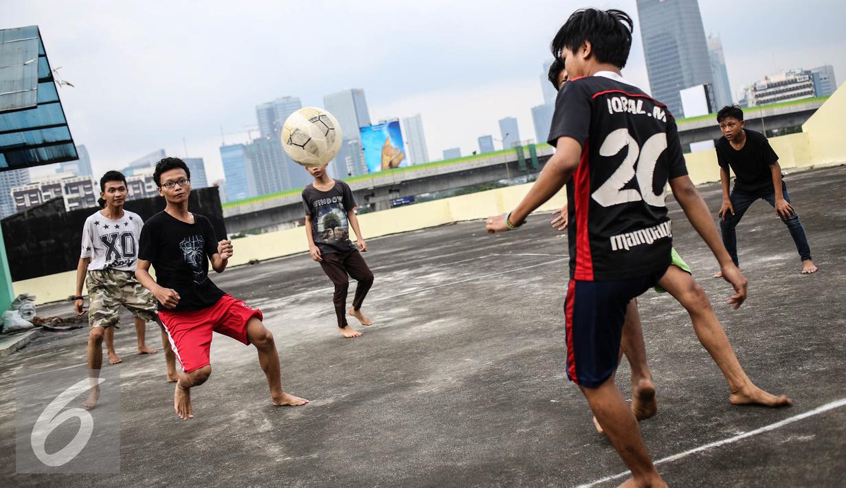Sejumlah remaja bermain futsal di atas gedung di Pasar Mampang, Jakarta, Rabu (12/7). Masih kurangnya lahan bermain di Jakarta, membuat warga khususnya anak-anak memanfaatkan fasilitas yang bukan peruntukannya. (Liputan6.com/Faizal Fanani)