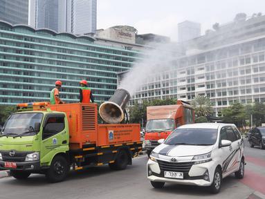 Petugas Dinas Lingkungan Hidup DKI Jakarta menyemprotkan kabut air (water mist) di sepanjang Jalan MH Thamrin, Jakarta Pusat, pada Senin (22/9/2025). (merdeka.com/Arie Basuki)