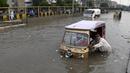 Seorang pengemudi mendorong bajaj saat melewati jalan yang banjir di Karachi, Pakistan, Kamis (23/9/2021). Banjir merendam Karachi setelah diguyur hujan deras. (AP Photo/Fareed Khan)
