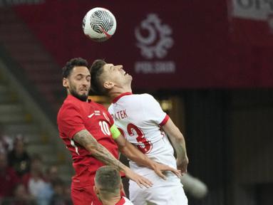 Penyerang Polandia Krzysztof Piatek berebut bola dengan gelandang Turki Hakan Calhanoglu dalam laga uji coba internasional terakhir jelang Euro 2024 di National stadium, Warsaw, Selasa (11/6/2024). (AP Photo/Czarek Sokolowski)