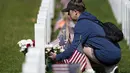 Seorang pengunjung meninggalkan karangan bunga di kuburan di Pemakaman Nasional Fort Logan, Sheridan, Colorado, Amerika Serikat, 30 Mei 2022. (AP Photo/David Zalubowski)
