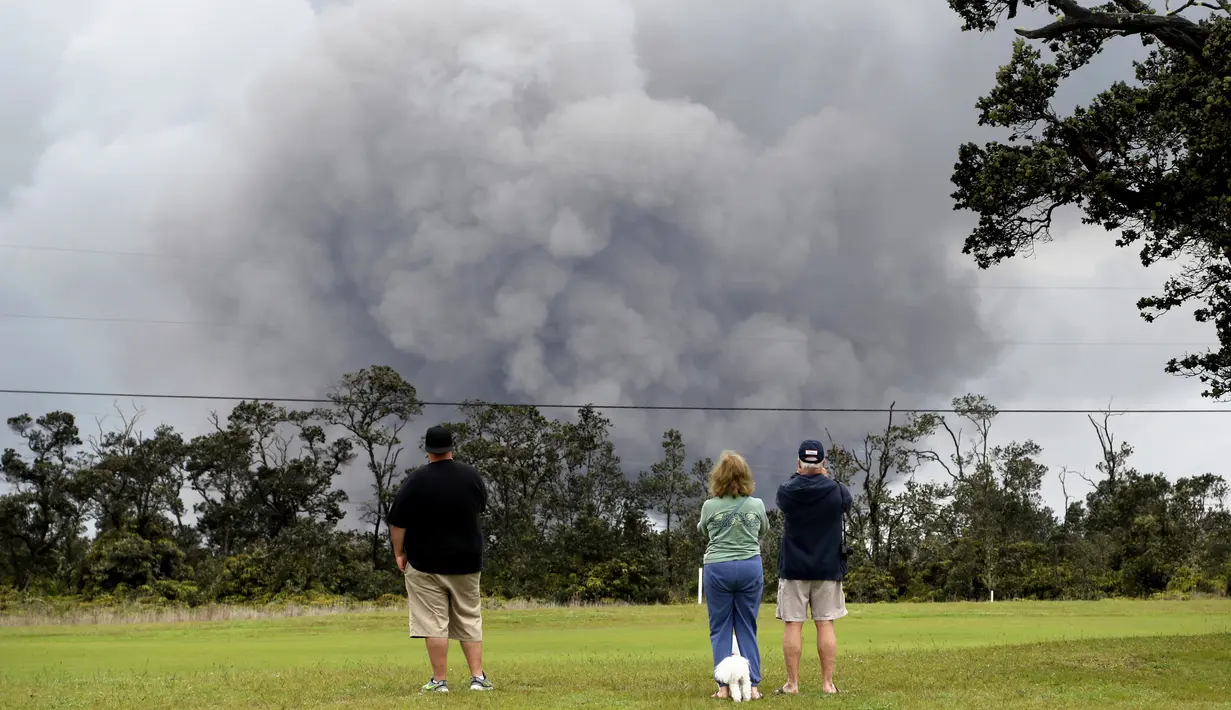 Wisatawan menyaksikan asap tebal yang berembus dari puncak gunung berapi Kilauea di Hawaii. Kamis (17/5). Para wisatawan tetap santai dan justru menjadikan letusan gunung ini sebagai objek wisata. (AP Photo/Caleb Jones)