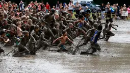 Ratusan anak berlari ke dalam lubang lumpur berisi ratusan ton lumpur saat perayaan Mud Day di Nankin Mills Park di Westland, Michigan, AS (11/7). (AFP Photo/Jeff Kowalsky)