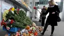 Seorang wanita meletakkan bunga di depan Bandara Internasional St. Petersburg di Rusia, Minggu (1/11). ini sebagai bentuk penghormatan kepada para penumpang yang menjadi korban jatuhnya pesawat Kogalymavia di Mesir. (AFP PHOTO/OLGA MALTSEVA)