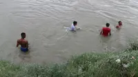 Puluhan warga menyelam untuk mencari keberadaan Riski (12 th) yang tenggelam di Sungai Palu. Sementara, sesekali buaya  menampakkan diri di tengah sungai dan pinggiran, Minggu (12/1/2020). (Foto: Liputan6.com/Heri Susanto)