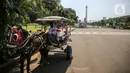 Pengemudi andong menunggu penumpang di depan kawasan Monumen Nasional (Monas), Jakarta, Minggu (26/7/2020). Sejumlah warga mulai mengunjungi kawasan Monas meski masih ditutup sementara di masa PSBB transisi. (Liputan6.com/Faizal Fanani)