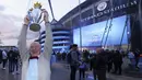 Seorang fans Manchester City mengangkat replika trofi juara Liga Inggris merayakan keberhasilan timnya memastikan merebut gelar juara Liga Inggris 2020/2021 di luar Etihad Stadium, Selasa (11/5/20221) sesaat setelah kekalahan Manchester United 1-2 oleh Leicester City di Old Trafford. (AP/Jon Super)