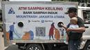 Warga memasukkan sampah minuman ringan saat menabung di ATM Sampah Keliling di Semper Barat, Cilincing, Jakarta Utara, Selasa (12/10/2021).  Bank Sampah Induk Mountrash Jakarta Utara membuat ATM Sampah Keliling sebagai upaya mengajak masyarakat untuk peduli sampah. (merdeka.com/Iqbal S. Nugroho)