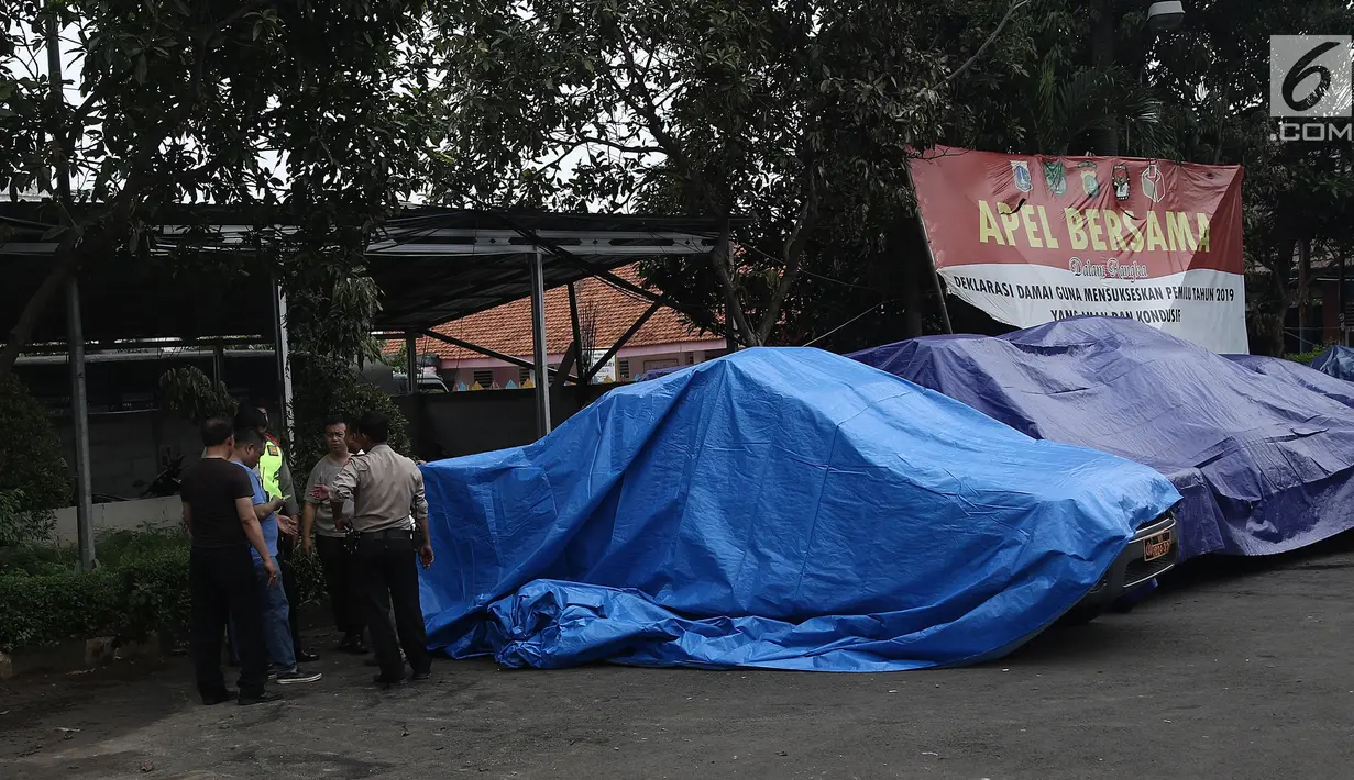 Terpal menutupi kendaraan yang terparkir di halaman Polsek Ciracas seusai perusakan dan pembakaran di Jakarta, Rabu (12/12). Belum diketahui tujuan massa mendatangi Polsek Ciracas hingga terjadi pembakaran pada dinihari tadi (Liputan6.com/Herman Zakharia)