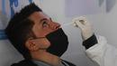 Petugas kesehatan mengambil sampel lendir hidung saa tes COVID-19 seorang penumpang, di bandara internasional Benito Juarez, Mexico City, Jumat (8/1/2022). Meksiko secara resmi mencatat 300.101 kematian sejak Maret 2020, termasuk 168 dalam 24 jam terakhir. (PEDRO PARDO/AFP)