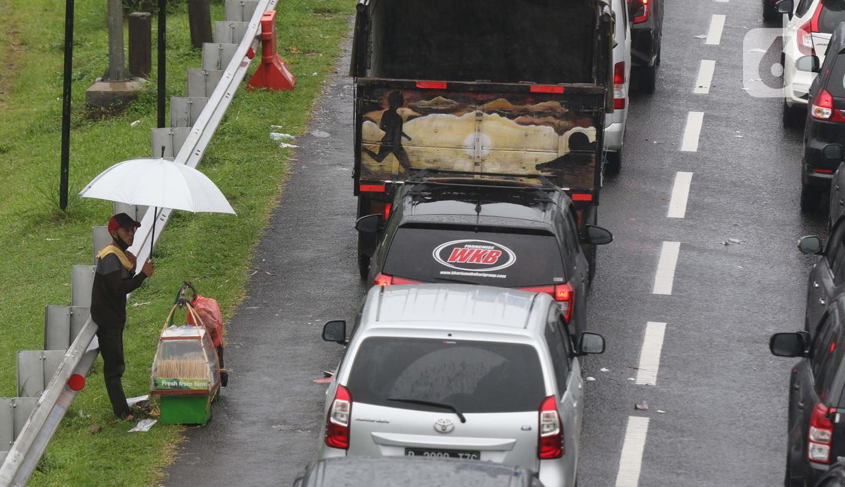 Seorang pedagang asongan menawarkan dagangan kepada pengendara di jalan tol Jagorawi yang sedang menanti waktu buka tutup jalur menuju kawasan wisata puncak, Bogor, Jawa Barat, Sabtu (31/10/2020). (Liputan6.com/Helmi Fithriansyah)
