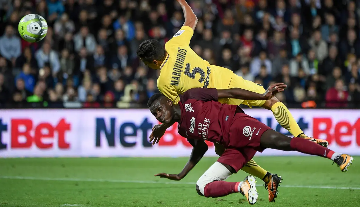 Bek PSG, Marquinhos, berebut bola dengan bek Metz, Moussa Niakhate, pada laga Ligue 1 Prancis di Stadion Saint-Symphorien, Moselle, Jumat (8/9/2017). Metz kalah 1-5 dari PSG. (AFP/Patrick Hertzog)