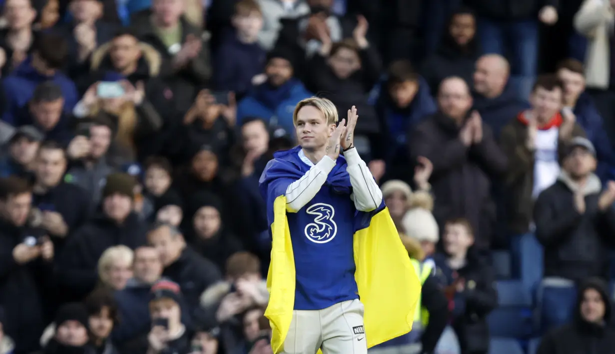 Membawa bendera Ukraina, Mykhailo Mudryk menyapa pendukung Chelsea pada paruh waktu pertandingan Liga Inggris Chelsea dan Crystal Palace di Stamford Bridge di London, Minggu 15 Januari 2023. Mykhailo Mudryk akan menggunakan nomor punggung 15 di Chelsea. (Mike Egerton/PA via AP)