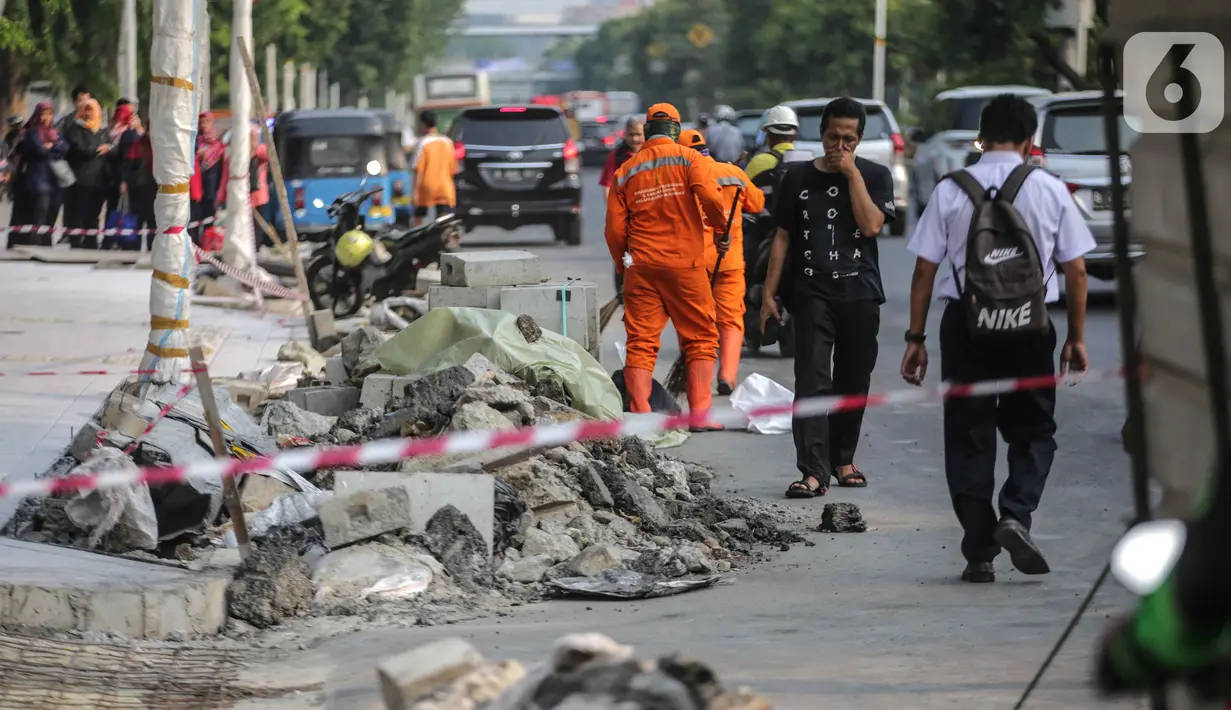 Pejalan kaki melintas dekat trotoar yang sedang direvitalisasi di kawasan Kramat Raya, Jakarta, Rabu (6/11/2019). Ketua Koalisi Pejalan Kaki Alfred Sitorus menilai pengerjaan revitalisasi trotoar membahayakan pejalan kaki karena tidak ada ruang sementara untuk melintas. (Liputan6.com/Faizal Fanani)