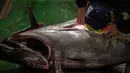 Pedagang grosir memeriksa tuna sirip biru selama pelelangan tuna Tahun Baru di pasar ikan Toyosu di Tokyo, Jepang, Rabu (5/1/2022). Dalam tradisi berbagai jenis ikan tuna berbagai ukuran hingga yang termahal ditampilkan dalam acara lelang Tahun Baru di pasar ikan Toyosu. (Philip FONG / AFP)