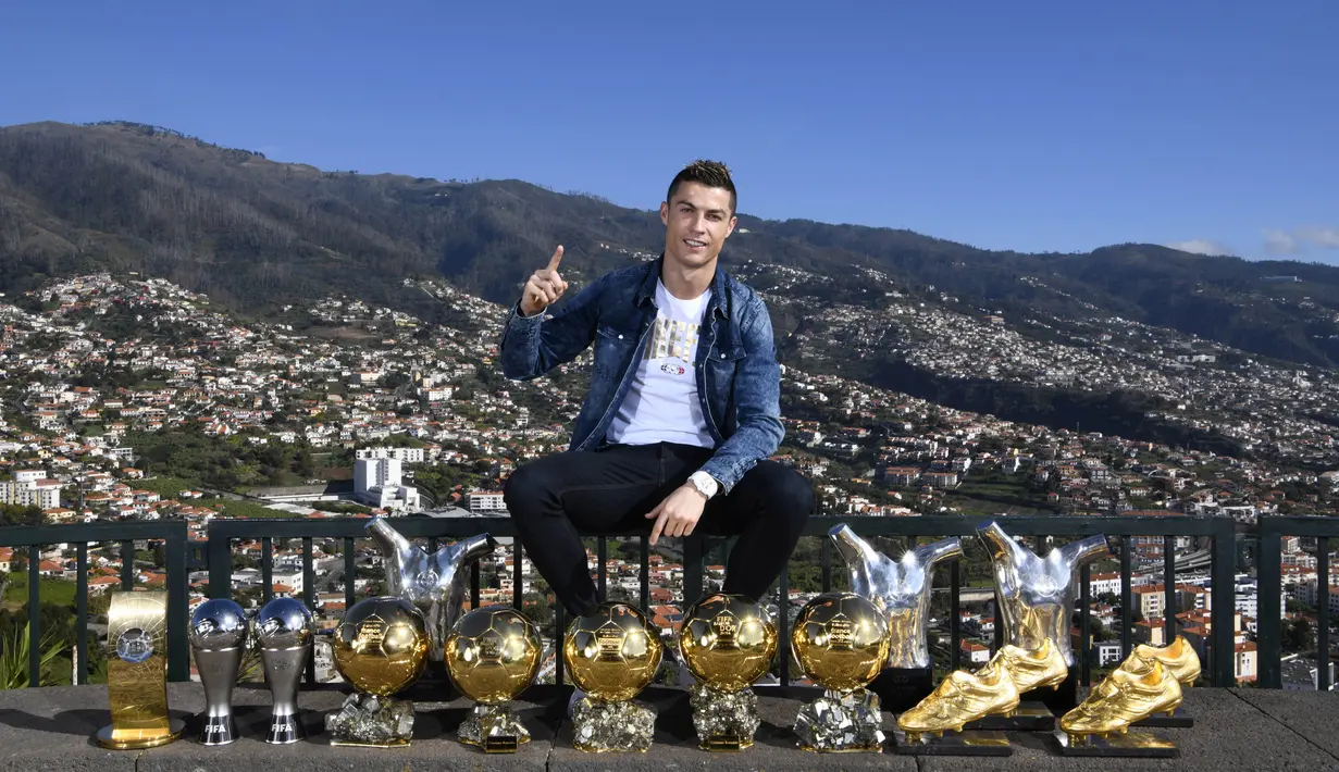 Bintang Real Madrid, Cristiano Ronaldo, berpose di depan trofi di kampung halamannya di Madeira, Portugal, Senin (1/1/2018). Pemain bernomor punggung tujuh itu memamerkan 15 trofi individual yang ia raih sebagai pemain terbaik. (AP/CR7 Media)