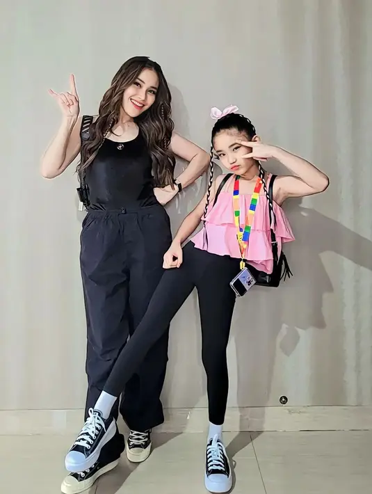 Sedangkan Bilqis masih setia dengan warna pink. Ia mengenakan atasan tanpa lengan berwarna pink, dipadu legging hitam, kaus kaki dan sepatu Converse putih. Gaya rambutnya juga unik, dikepang dua kecil, lalu diberi pemanis pita pink. [Foto: Instagram/ayutingting92]