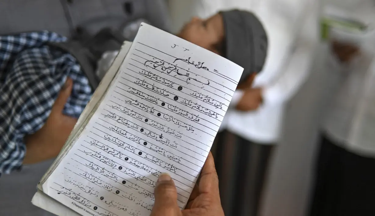 Orang-orang berdoa untuk bayi yang baru lahir saat prosesi aqiqah di Banda Aceh, Aceh, 4 November 2021. Aqiqah adalah tradisi menyambut bayi yang baru lahir dalam agama Islam. (CHAIDEER MAHYUDDIN/AFP)