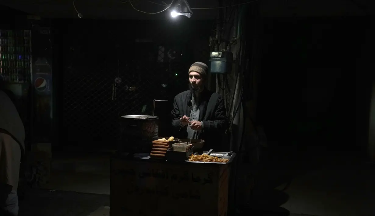 Seorang pedagang menggunakan lampu alternatif di kios kentang gorengnya di sebuah pasar selama pemadaman listrik di seluruh negeri, di Islamabad, Pakistan, Senin, 23 Januari 2023. Listrik padam di pabrik, rumah sakit dan sekolah di seluruh penjuru negara itu selama berjam-jam setelah fluktuasi tegangan di antara Kota Jamshoro dan Kota Dadu di Provinsi Sidh selatan. (AP Photo/K.M. Chaudary)