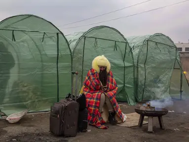 Seorang perempuan terbungkus selimut mencoba untuk tetap hangat setelah melarikan diri dari Ukraina dan tiba di perbatasan di Medyka, Polandia, Senin (7/3/2022). Hampir 2 juta orang telah melarikan diri sejak Rusia menginvasi Ukraina dengan jumlah itu meningkat setiap hari. (AP Photo/Visar Kryeziu)