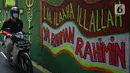 Pengendara melintasi mural bernuansa Islami di Gang Pelangi, kawasan Kalibata, Jakarta, Jumat (23/4/2021). Mural bernuansa Islami tersebut dibuat warga untuk menghiasi dan meramaikan pintu masuk gang dalam rangka menyambut bulan Ramadhan. (Liputan6.com/Herman Zakharia)
