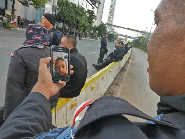 Seorang anggota Brimob melakukan panggilan video dengan anaknya disela penjagaan di kawasan MH Thamrin, Jakarta, Jumat (24/5/2019). Usai kerusuhan 22 Mei 2019, penjagaan di kawasan jalan MH Thamrin sampai Jumat, 24 Mei 2019 masih terus dilakukan oleh aparat kepolisian. (Liputan6.com/Herman Zakharia)