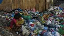 Dua orang anak melihat sepatu saat menyortir sampah di permukiman kumuh di sepanjang garis pantai Pantai Baseco di Manila (28/9/2019). Daerah ini rawan banjir akibat angin topan dan hujan lebat. (AFP Photo/Maria Tan)