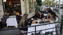 Orang-orang makan di sebuah restoran untuk mereka yang sudah divaksinasi di Tel Aviv, Minggu (7/3/2021). Israel mengambil langkah lain menuju keadaan normal pasca-pandemi, dengan sekitar 40 persen populasi sepenuhnya telah diinokulasi untuk melawan virus corona COVID-19.  (Emmanuel DUNAND/AFP)