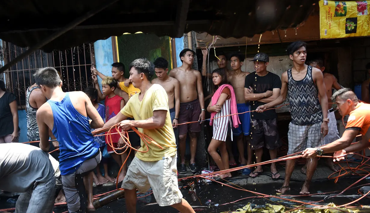 Sejumlah warga mencoba mengambil sisa kabel listrik saat insiden kebakaran sebuah pemukiman padat penduduk dekat pelabuhan di Manila, Filipina, Selasa (9/5). Mereka berebut mengumpulkan tembaga dari sisa kabel listrik. (TED ALJIBE/AFP)