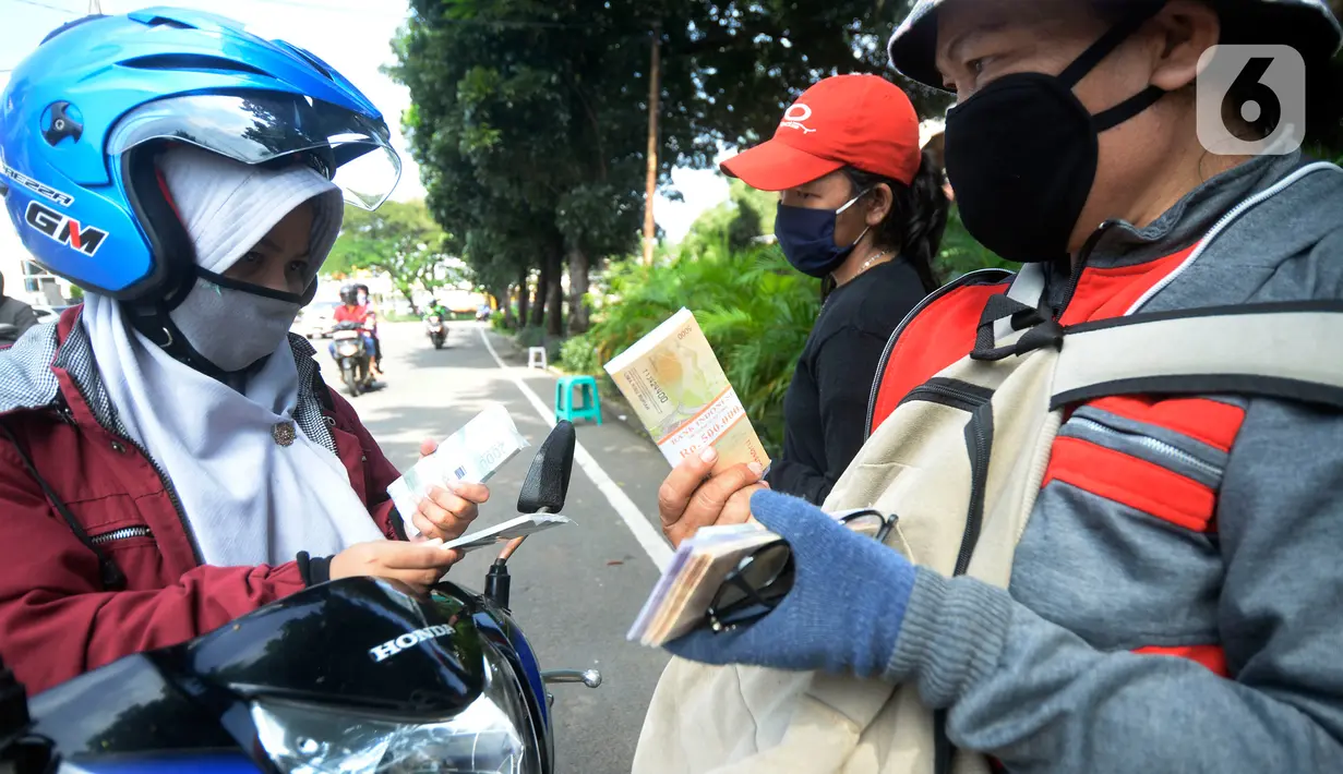Pengguna jalan membeli uang baru yang dijajakan penjual jasa penukaran uang di kawasan Bintaro Sektor 2, Jakarta Selatan, Selasa (12/05/2020). Menjelang perayaan Lebaran, jasa penukar uang keliling yang berada di pinggir jalan-jalan utama mulai bermunculan. (merdeka.com/Dwi Narwoko)