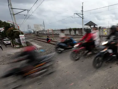 Pengendara motor melewati perlintasan kereta api tanpa palang pintu di kawasan Kelingkit, Rawa Buaya, Jakarta, Selasa (26/2). Rel kereta tanpa adanya palang pintu penutup ini sangat berbahaya karena bisa menyebabkan kecelakaan. (Liputan6.com/Johan Tallo)