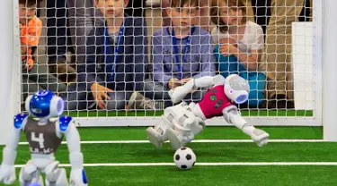 Robot penjaga gawang tim 'Nomadz' Swiss berhasil menahan bola saat melawan robot tim 'Hulk' dari Jerman dalam pertandingan kompetisi Liga Platform Standar di RoboCup GermanOpen 2018, Magdeburg, Jerman (28/4). (AP/Jens Meyer)