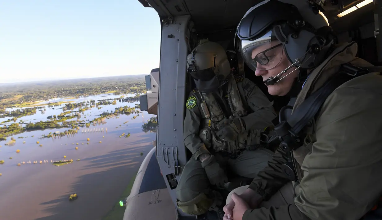 PM Australia Scott Morrison (kanan) mengecek banjir di barat laut Sydney, Australia, Rabu (24/3/2021).  Sekitar 18.000 penduduk negara bagian terpadat di Australia telah meninggalkan rumah mereka sejak pekan lalu, dengan peringatan banjir dapat berlanjut hingga April. (Lukas Coch/Pool Photo via AP)
