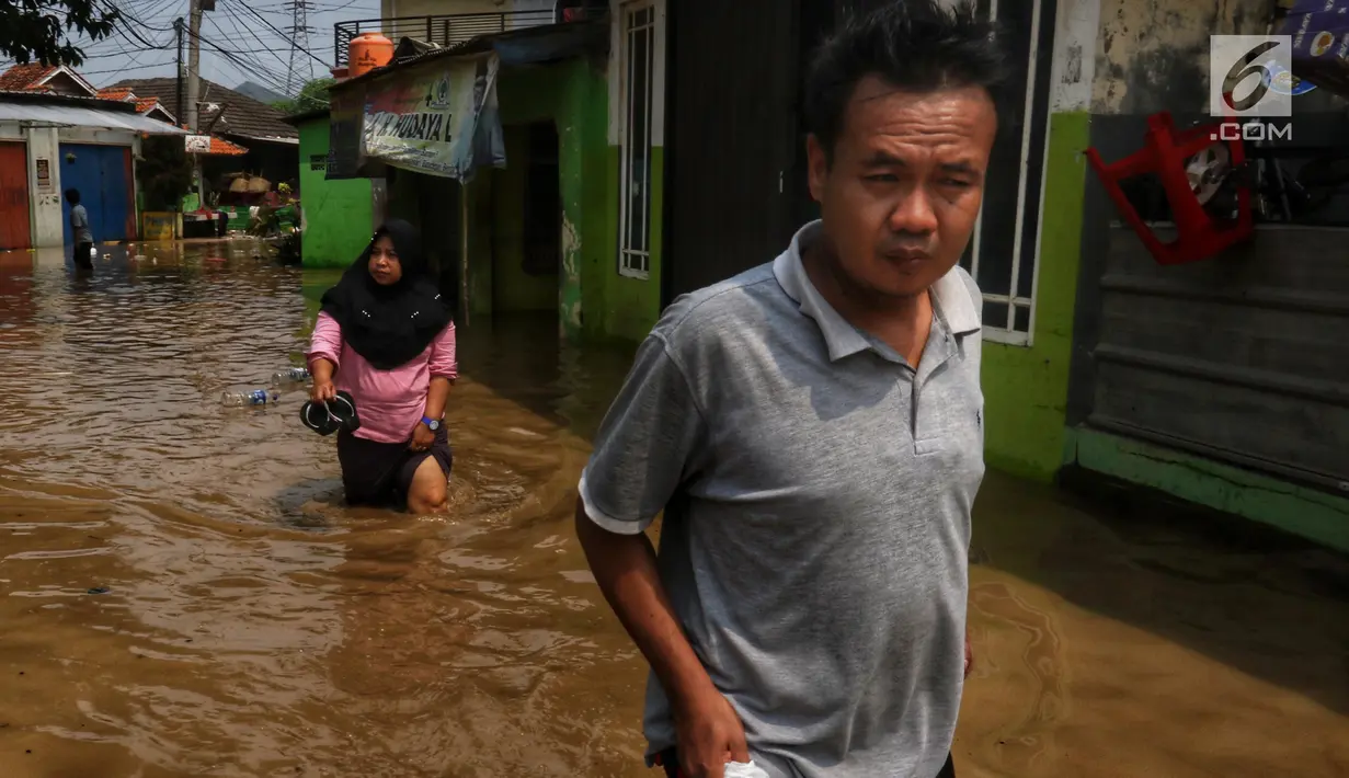 Warga melintasi banjir yang melanda kawasan bantaran kali Cisadane, Tangerang, Jumat (26/4). Banjir kiriman setinggi 2 meter sempat melanda kawasan akibat curah hujan yang tinggi di bogor membuat derasnya air mengalir jauh sampai ke tempat ini. (Liputan6.com/Johan Tallo)