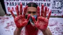 Aktivis melakukan teatrikal dengan menyiramkan darah di tubuhnya saat aksi serentak desak Presiden Jokowi deklarasikan Darurat Iklim di kawasan Patung Kuda, Jakarta, Jumat (19/3/2021). Aksi ini sebagai simbol banyaknya bencana yang terjadi di Indonesia. (Liputan6.com/Faizal Fanani)
