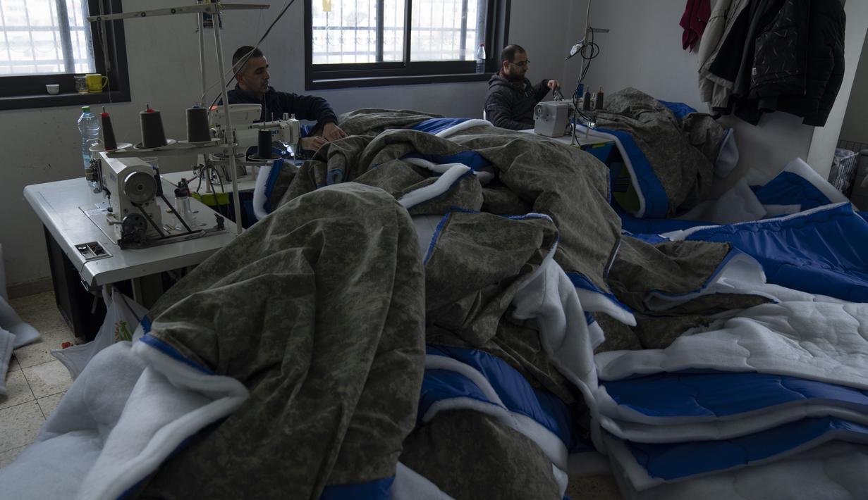 Penjahit memproduksi dan menyiapkan pengiriman massal perlengkapan tidur untuk korban gempa bumi di Turki dan Suriah yang sekarang terkena cuaca musim dingin yang membekukan, di sebuah pabrik Palestina di kota Hebron, Tepi Barat, Kamis (16/2/2023). Warga Palestina telah turun tangan untuk membantu mereka yang terguncang akibat gempa dahsyat di Turki dan Suriah, dengan Otoritas Palestina bahkan mengirim tim medis dan ahli lainnya untuk mendukung upaya penyelamatan. (AP Photo/Nasser Nasser)