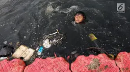 Seorang anak berenang di antara sampah di Kanal Banjir Barat (KBB), Petamburan, Jakarta, Senin (12/8/2019). Surutnya debit air KBB akibat musim kemarau dimanfaatkan anak-anak untuk bermain sambil mencari ikan. (Liputan6.com/Fery Pradolo)