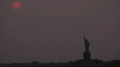 Matahari terbenam di atas Patung Liberty di New York City, Amerika Serikat pada 22 Mei 2023. (Spencer Platt/Getty Images/AFP)