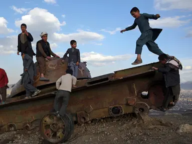 Anak-anak Afghanistan bermain di sisa-sisa tank Soviet di puncak bukit di pinggiran Kabul, Afghanistan (4/3). Mereka sering menghabiskan waktunya dengan bermain di sebuah tank yang sudah hancur dan hasil sitaan para pejuang. (AP Photo/Rahmat Gul)