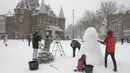 Orang-orang membuat boneka salju di tengah Amsterdam, karena salju dan angin kencang menyelimuti sebagian besar wilayah Belanda, Minggu (7/2/2021). (AP Photo/Peter Dejong)