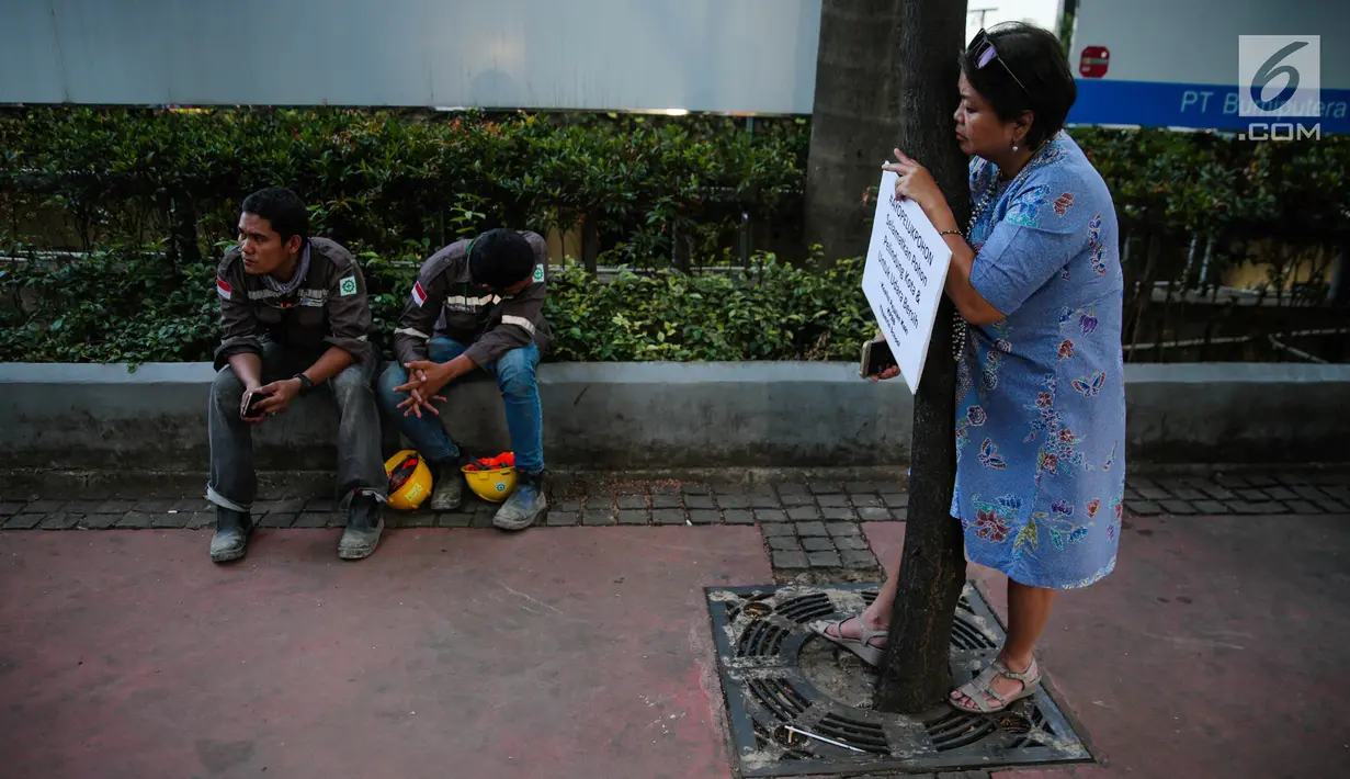 Seorang wanita dari Koalisi Pejalan Kaki, KPBB, dan Thamrin School of Climate Change and Sustainability menggelar aksi #ayopelukpohonini di Jalan Sudirman, Jakarta, Jumat (22/9). (Liputan6.com/Faizal Fanani)