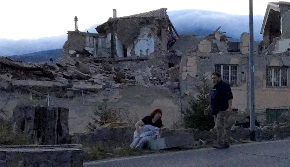 Dua orang warga melarikan diri ke jalan menyusul  gempa 6,2 SR yang melanda Amatrice, Italia tengah, Kamis (24/8). Petugas berwenang melaporkan, sedikitnya enam orang tewas dalam bencana ini. (REUTERS/Emiliano Grillotti)