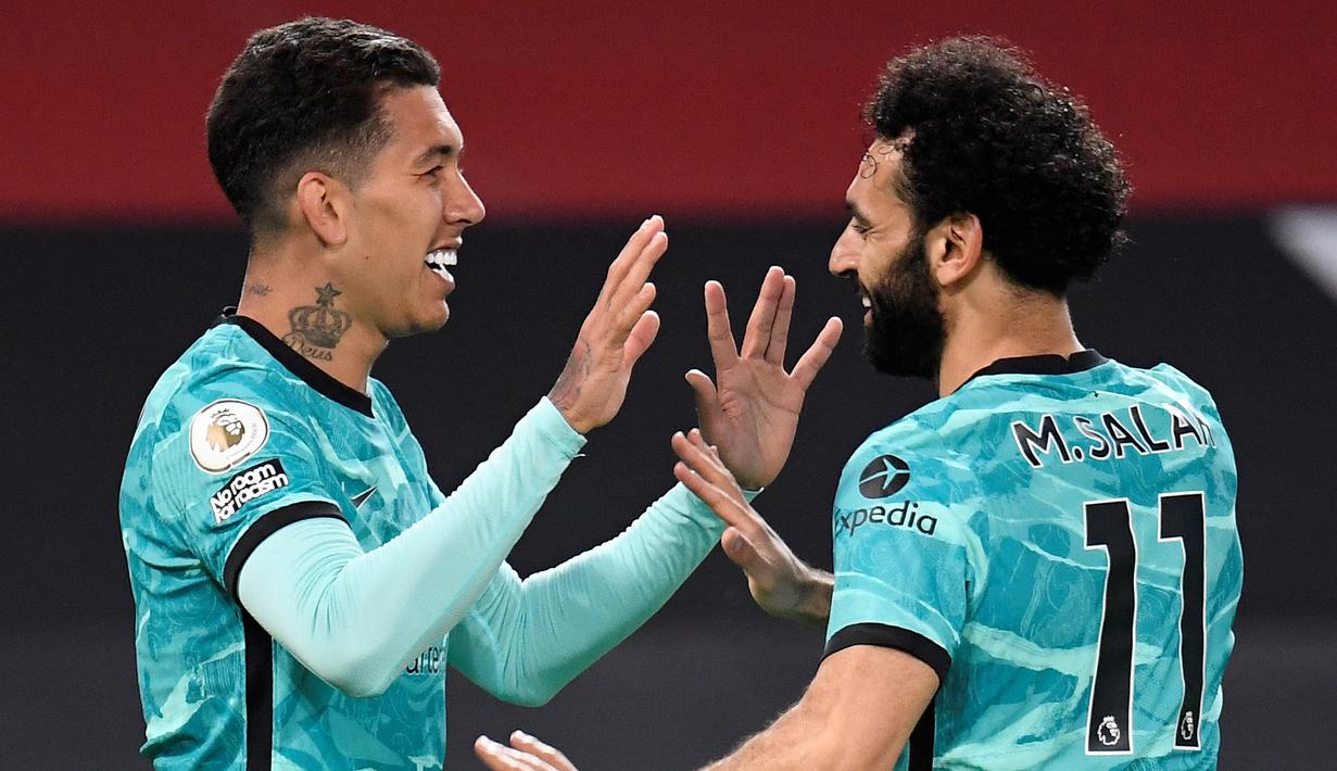 Gelandang Liverpool, Roberto Firmino (kiri) melakukan selebrasi usai mencetak gol ketiga timnya ke gawang Manchester United dalam laga lanjutan Liga Inggris 2020/2021 pekan ke-35 di Old Trafford, Kamis (13/5/2021). Liverpool menang 4-2 atas Manchester United. (AFP/Peter Powell/Pool)