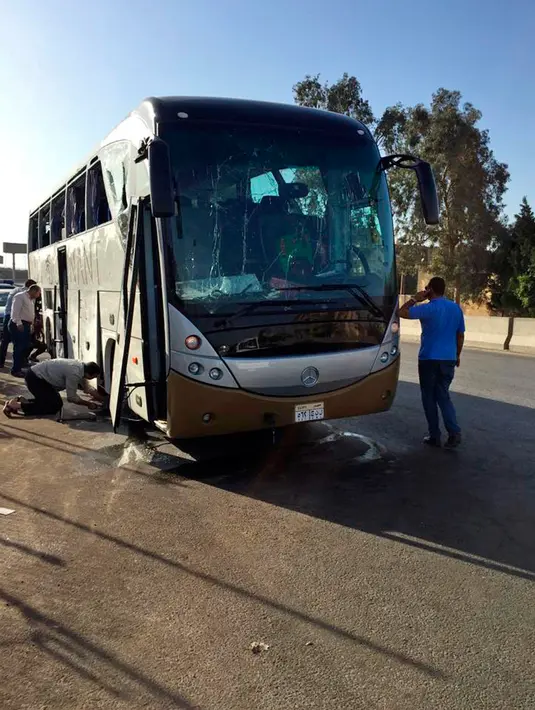 Petugas memeriksa sebuah bus wisata dan mobil yang rusak setelah ledakan bom di jalan dekat Piramida Giza, Kairo, Minggu (19/5/2019). Ledakan yang berasal dari bom pinggir jalan itu menghantam sebuah bus yang sedang melaju di Giza dan sebuah mobil di dekatnya. (AP Photo/Mohammed Salah)