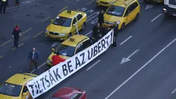 Sejumlah Sopir taksi membawa tulisan menolak layanan taksi online Uber di Budapest, Hongaria, (18/1). Tuntutan mereke berisi tentang resiko adanya aplikasi Uber terhadap pekerjaan mereka.  (AFP / Ferenc ISZA)