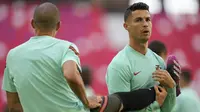 Penyerang Portugal, Cristiano Ronaldo berdiri di samping rekan setimnya Pepe selama sesi latihan di arena stadium di Munich, Jumat (18/6/2021). Portugal akan bertanding melawan Jerman pada grup F Euro 2020 di Allianz Arena. (AP Photo/Matthias Schrader)